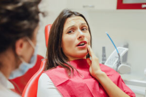 Close-up portrait of a sad young girl with a painful tooth, a doctor in office chairs, an isolated dentist office background clinic. Expressions of the human face, emotions, feelings, reactions