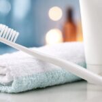 Toothbrush and toothpaste tube resting on a folded towel, symbolizing daily oral hygiene and personal healthcare routine