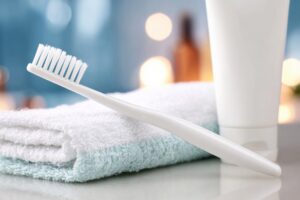 Toothbrush and toothpaste tube resting on a folded towel, symbolizing daily oral hygiene and personal healthcare routine